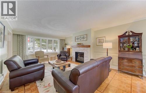 Living area featuring a stone-clad fireplace with a wood mantel, a multi-pane bay window, and wood-finish flooring - 514 Colonial Drive, Waterloo, ON - Indoor Photo Showing Living Room With Fireplace