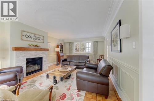 Living area featuring a fireplace with a light-colored stacked stone surround and a wood mantel - 514 Colonial Drive, Waterloo, ON - Indoor Photo Showing Living Room With Fireplace