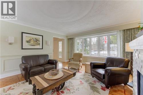 Living room featuring a large bay window, wood-finish flooring, crown molding, and wainscoting - 514 Colonial Drive, Waterloo, ON - Indoor Photo Showing Living Room With Fireplace