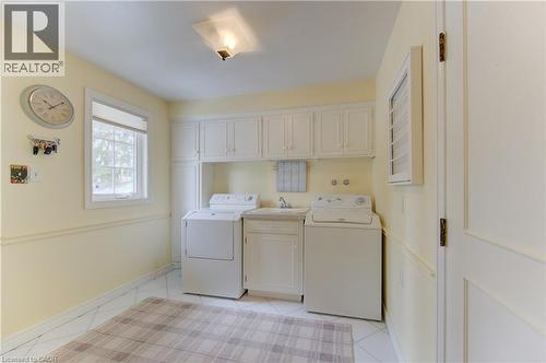 Laundry area featuring white cabinetry, a built-in utility sink, and tile flooring - 514 Colonial Drive, Waterloo, ON - Indoor Photo Showing Laundry Room
