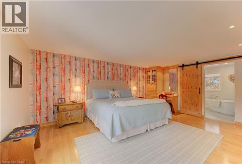 Hardwood flooring extends throughout this spacious room, featuring a decorative accent wall and recessed lighting - 514 Colonial Drive, Waterloo, ON - Indoor Photo Showing Bedroom