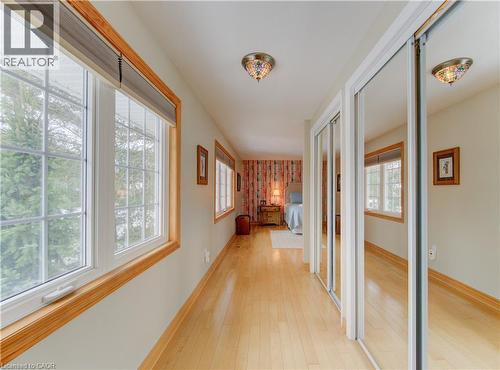 Hallway featuring light wood-finish flooring, multiple windows with wood trim, and mirrored sliding closet doors - 514 Colonial Drive, Waterloo, ON - Indoor Photo Showing Other Room