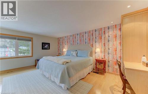 Room featuring a statement wall with a birch tree pattern, light wood-finish flooring, a large window with natural wood trim, recessed ceiling lighting, and built-in cabinetry - 514 Colonial Drive, Waterloo, ON - Indoor Photo Showing Bedroom