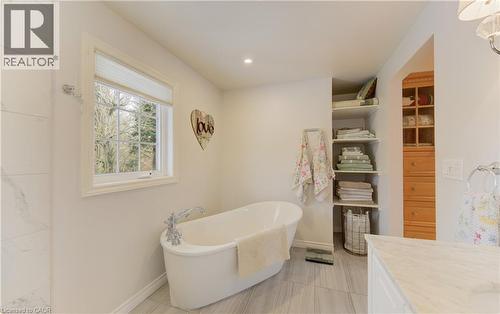 Freestanding soaking tub with chrome fixtures, set against light gray tile flooring - 514 Colonial Drive, Waterloo, ON - Indoor Photo Showing Bathroom
