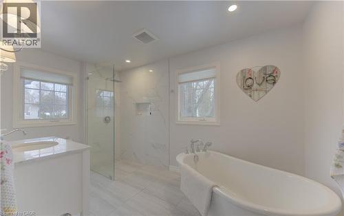 Contemporary bathroom featuring a freestanding soaking tub, a glass-enclosed shower with tiled walls and an integrated niche, a single vanity with a white countertop and undermount sink, and recessed - 514 Colonial Drive, Waterloo, ON - Indoor Photo Showing Bathroom
