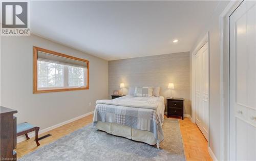 Bedroom featuring wood-finish flooring, a neutral color palette, and built-in closet doors with decorative paneling - 514 Colonial Drive, Waterloo, ON - Indoor Photo Showing Bedroom