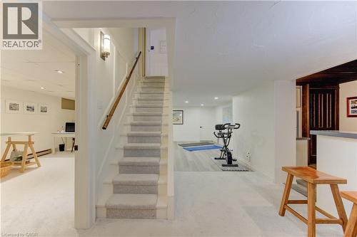 Carpeted staircase with wooden handrail, featuring recessed lighting and a wall-mounted sconce - 514 Colonial Drive, Waterloo, ON - Indoor Photo Showing Other Room