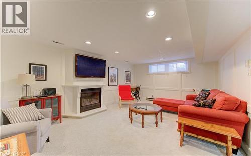 Carpeted recreation room featuring a corner fireplace with a mounted television above - 514 Colonial Drive, Waterloo, ON - Indoor With Fireplace
