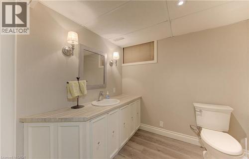 Bathroom featuring a white vanity with a stone-look countertop, undermount sink, and wall-mounted sconces - 514 Colonial Drive, Waterloo, ON - Indoor Photo Showing Bathroom
