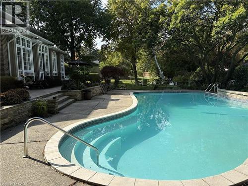 Curved inground pool with integrated steps and a surrounding concrete patio - 514 Colonial Drive, Waterloo, ON - Outdoor With In Ground Pool With Backyard