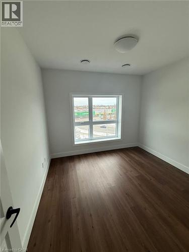 Empty room with dark wood-style flooring and baseboards - 1000 Lackner Place Unit# 401, Kitchener, ON - Indoor Photo Showing Other Room