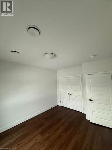 Unfurnished bedroom with a closet, dark wood-style floors, and baseboards - 1000 Lackner Place Unit# 401, Kitchener, ON - Indoor