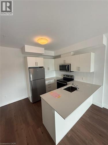 Kitchen featuring light countertops, stainless steel appliances, dark wood finished floors, a sink, and a peninsula - 1000 Lackner Place Unit# 401, Kitchener, ON - Indoor Photo Showing Kitchen