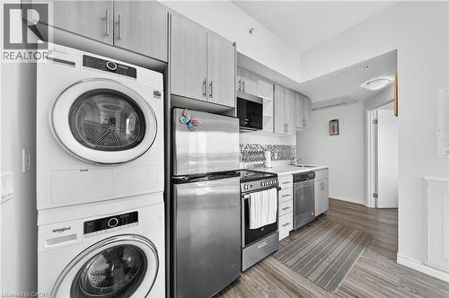 Compact kitchen featuring light wood-finish cabinetry, stainless steel appliances, a tile backsplash, and wood-finish flooring - 246 Lester Street Unit# Ph-03, Waterloo, ON - Indoor Photo Showing Laundry Room