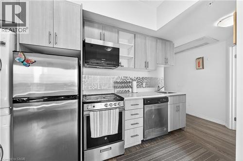 Compact kitchen featuring wood-finish cabinetry, stainless steel appliances, mosaic tile backsplash, and wood-finish flooring - 246 Lester Street Unit# Ph-03, Waterloo, ON - Indoor Photo Showing Kitchen With Upgraded Kitchen