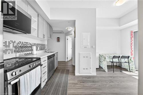 Modern kitchen featuring light wood-finish cabinetry, stainless steel appliances, a mosaic tile backsplash, and light countertops - 246 Lester Street Unit# Ph-03, Waterloo, ON - Indoor Photo Showing Kitchen