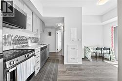 Modern kitchen featuring light wood-finish cabinetry, stainless steel appliances, a mosaic tile backsplash, and light countertops - 