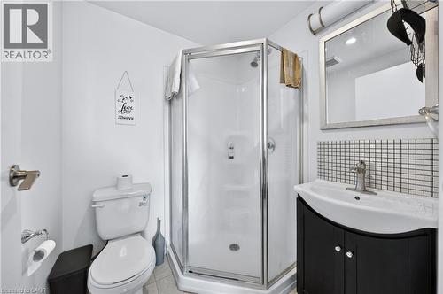 Compact bathroom featuring a corner shower with glass enclosure, white toilet, and a vanity with a dark cabinet and integrated sink - 246 Lester Street Unit# Ph-03, Waterloo, ON - Indoor Photo Showing Bathroom