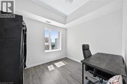 Bright room featuring wood-finish flooring, white baseboards, a large window, and high ceilings with tray detailing - 