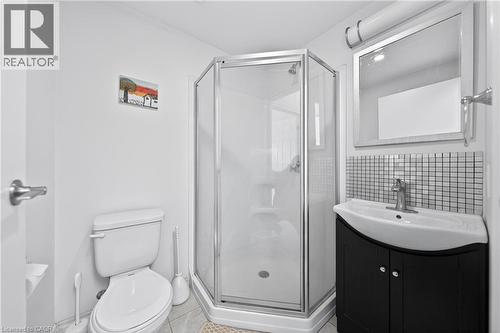 Compact bathroom featuring a corner shower enclosure with clear glass, a black vanity with an integrated sink, a tiled backsplash, and a wall-mounted mirror with overhead lighting - 246 Lester Street Unit# Ph-03, Waterloo, ON - Indoor Photo Showing Bathroom