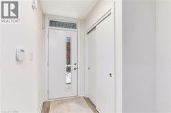 Entryway featuring a white door with vertical glass insert, transom window, and wood-finish flooring - 