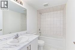 Bathroom featuring a white bathtub, ceramic tile shower surround, and a vanity with a white countertop and integrated sink - 