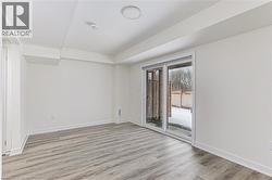 Room featuring wood-finish flooring, white baseboards, and bright white walls - 