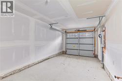 Spacious garage featuring a light gray sectional door with upper window inserts, concrete flooring, and unfinished drywall - 