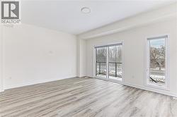 Spacious room featuring wood-finish flooring, white baseboards, and a circular flush-mount ceiling light - 