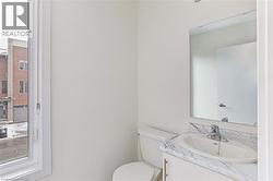 Powder room featuring a white single vanity with a marble-finish countertop, under-mount sink, and a framed mirror - 