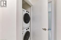 Dedicated laundry closet featuring a stacked white washer and dryer unit - 