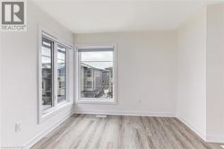 Corner room with two large windows, wood-finish flooring, white walls, white trim, and roller shades - 