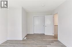 Room featuring wood-finish flooring, white baseboards, and a white ceiling - 