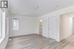 Spacious room with wood-finish flooring, multiple windows, and a flush-mount ceiling light - 