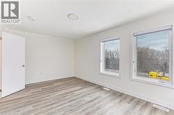 Bright room featuring light wood-finish flooring and white baseboards - 