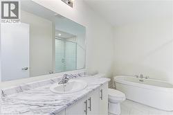 Bathroom featuring a free-standing soaking tub, a glass-enclosed shower, a vanity with a white-finish cabinet, a single-basin sink, and a stone-patterned countertop - 