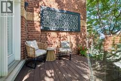 Outdoor balcony with dark composite decking, brick exterior wall, and a decorative geometric wall panel - 