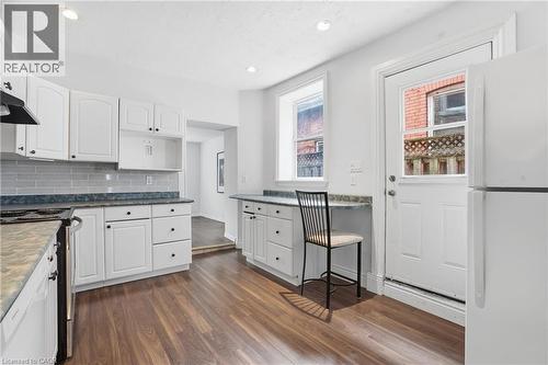 Kitchen featuring white cabinetry, wood-finish flooring, recessed lighting, subway tile backsplash, and an exterior door with integrated window - 137 Market Street, Hamilton, ON - Indoor Photo Showing Kitchen