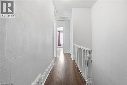 Wood-finish flooring throughout a hallway with white painted walls and baseboards - 137 Market Street, Hamilton, ON - Indoor Photo Showing Other Room