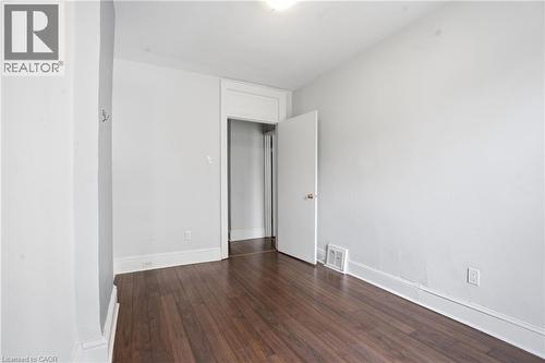 Spacious room featuring wood-finish flooring, white baseboards, and a doorway with classic trim - 137 Market Street, Hamilton, ON - Indoor Photo Showing Other Room