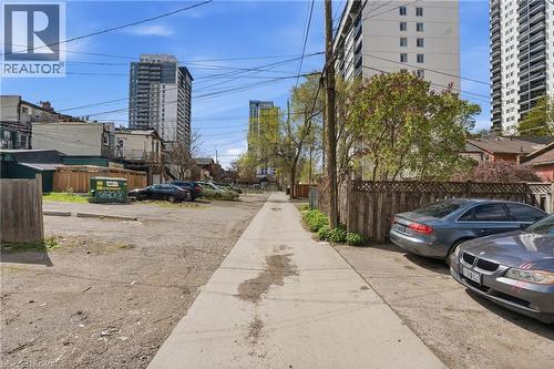 Paved alleyway bordered by wooden fencing and concrete curbstones, with tall buildings in the background - 137 Market Street, Hamilton, ON - Outdoor
