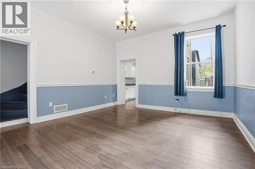 Spacious interior featuring wood-finish flooring, a decorative ceiling medallion with an attached chandelier, and a large window providing natural light - 137 Market Street, Hamilton, ON - Indoor Photo Showing Other Room