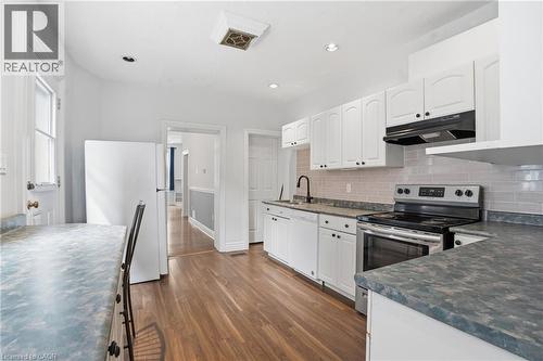 Kitchen featuring wood-finish flooring, white cabinetry, integrated stainless steel range, and subway tile backsplash - 137 Market Street, Hamilton, ON - Indoor Photo Showing Kitchen With Upgraded Kitchen