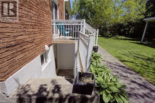 Exterior featuring a brick facade with a white lower foundation, a concrete patio, a private exterior entrance, and a white metal railing - 2344 Brinell Avenue, Burlington, ON - Outdoor