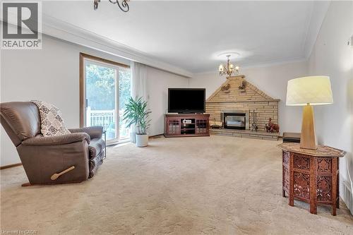 Spacious living area featuring a corner stone fireplace with an integrated mantel, plush carpet flooring, and a sliding glass door providing exterior access - 2344 Brinell Avenue, Burlington, ON - Indoor Photo Showing Living Room With Fireplace