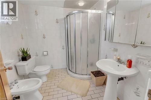 Bathroom featuring white subway tile walls with decorative accents, a corner shower enclosure, a pedestal sink, and white tile flooring - 2344 Brinell Avenue, Burlington, ON - Indoor Photo Showing Bathroom