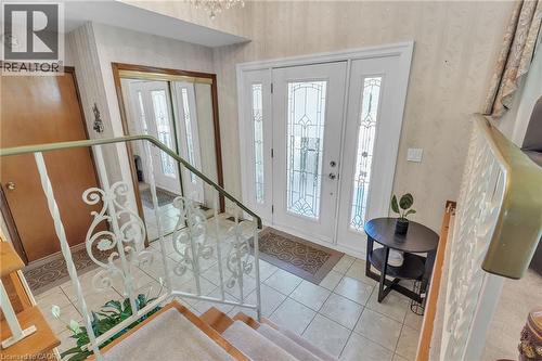 Entryway featuring a white double door with decorative glass inserts, ceramic tile flooring, and a wrought iron staircase railing - 2344 Brinell Avenue, Burlington, ON - Indoor Photo Showing Other Room