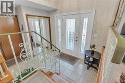 Entryway featuring a white double door with decorative glass inserts, ceramic tile flooring, and a wrought iron staircase railing - 