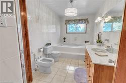 Full bathroom featuring a built-in jetted tub, dual-sink vanity with a light-toned countertop, and tiled flooring - 