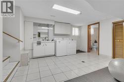 Tiled flooring throughout a utility space featuring a laundry area with built-in cabinetry, a utility sink, and a washer and dryer - 